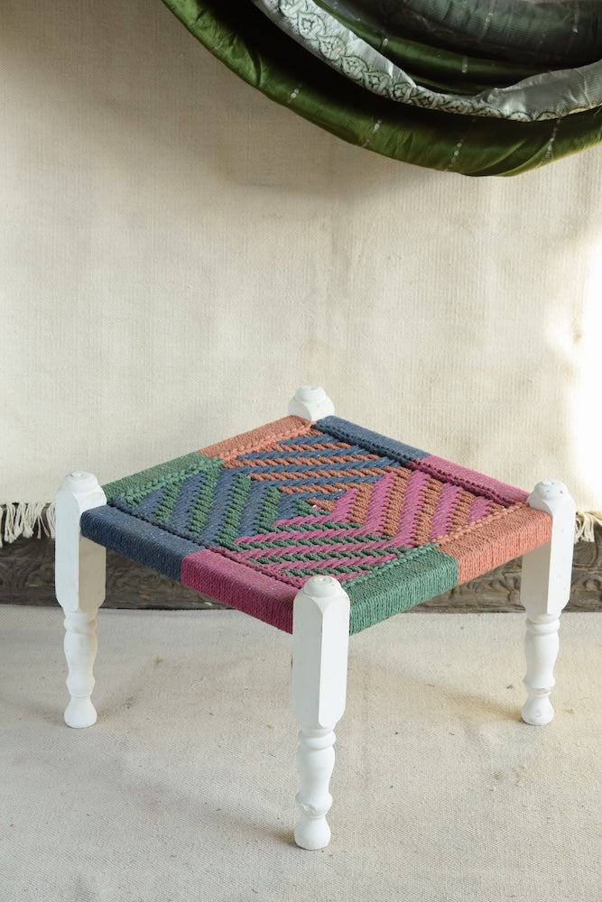 Handcrafted charpai-inspired wooden stool with handwoven cotton seat, featuring traditional Indian weaving and vibrant patterns by Ekaurr