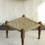 Handcrafted charpai-inspired wooden stool with handwoven cotton seat, featuring traditional Indian weaving and vibrant patterns by Ekaurr