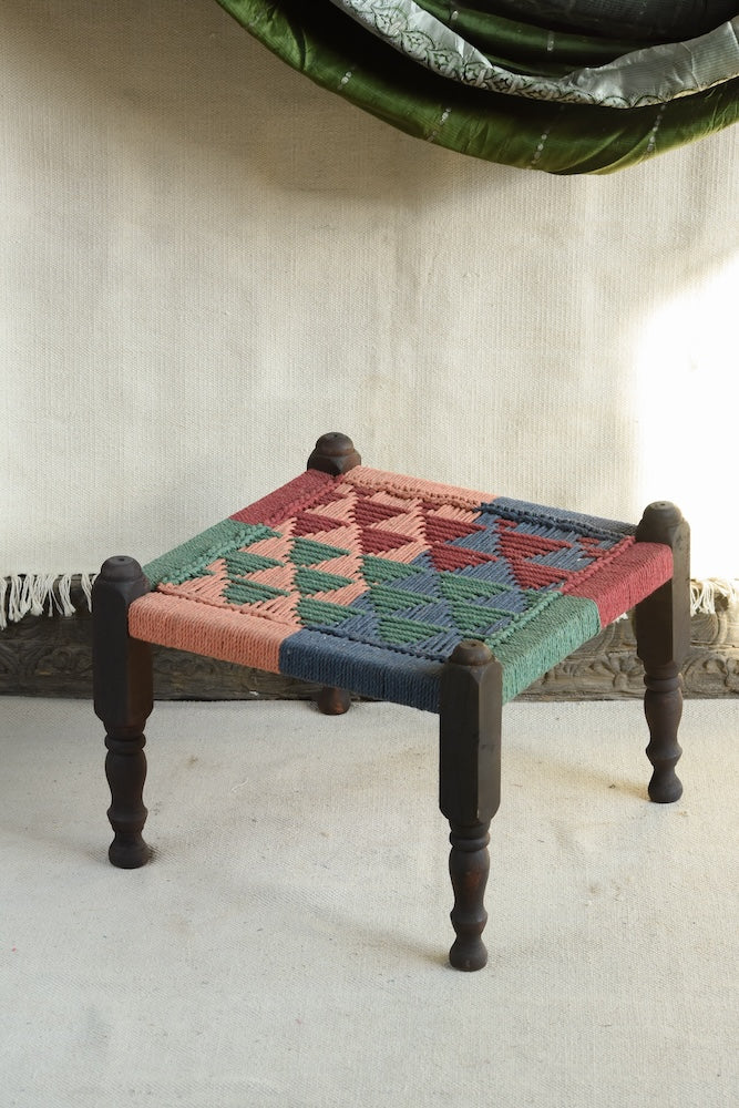 Handcrafted charpai-inspired wooden stool with handwoven cotton seat, featuring traditional Indian weaving and vibrant patterns by Ekaurr