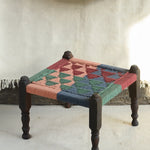 Handcrafted charpai-inspired wooden stool with handwoven cotton seat, featuring traditional Indian weaving and vibrant patterns by Ekaurr
