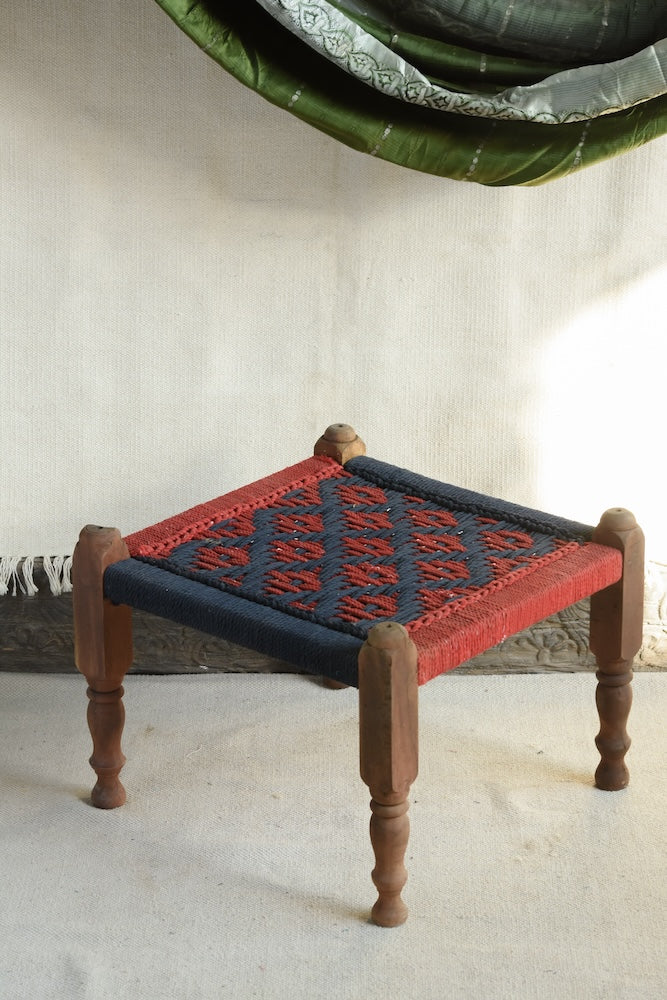 Handcrafted charpai-inspired wooden stool with handwoven cotton seat, featuring traditional Indian weaving and vibrant patterns by Ekaurr