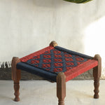 Handcrafted charpai-inspired wooden stool with handwoven cotton seat, featuring traditional Indian weaving and vibrant patterns by Ekaurr