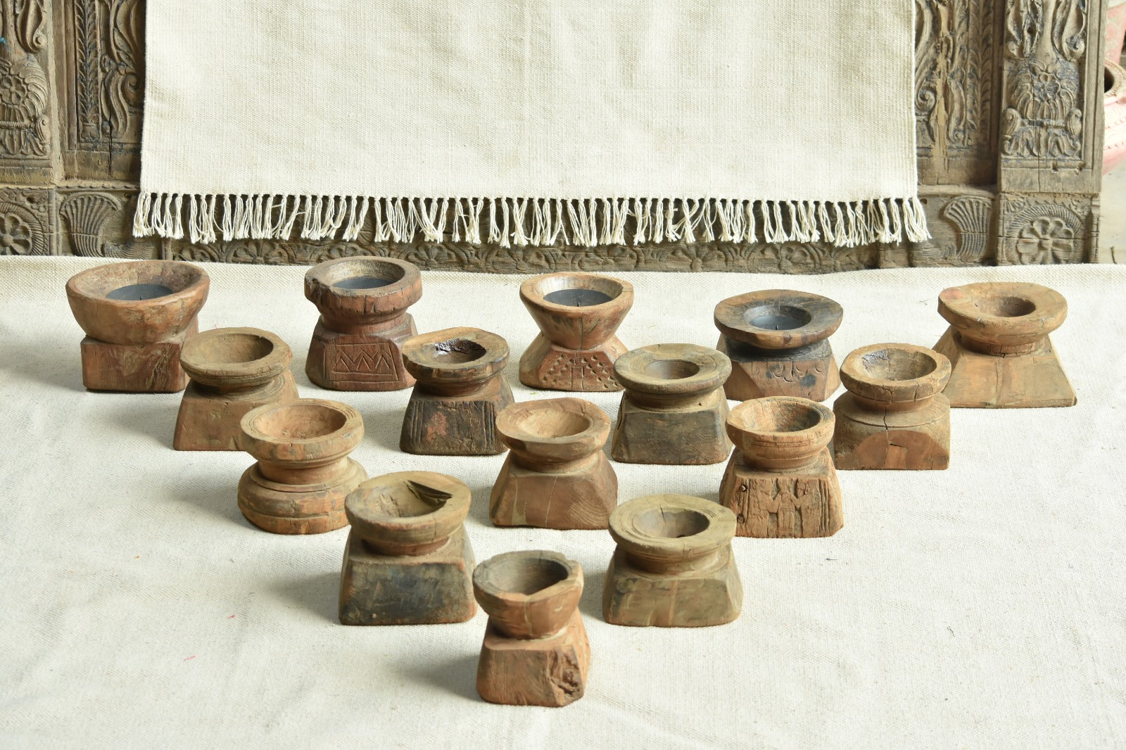 Group display of Ekaurr Bijani wooden candle holders showing variety of hand-carved textures and natural patina of vintage Indian seed dispensers