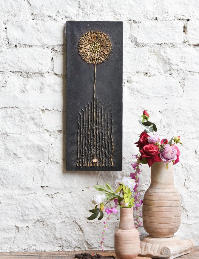 Ekaurr Bloom in Stillness mixed-media wall art of a dandelion-inspired bloom with golden textured detailing on a matte black base at 32x12 inches, handcrafted botanical home decor for modern rustic living rooms