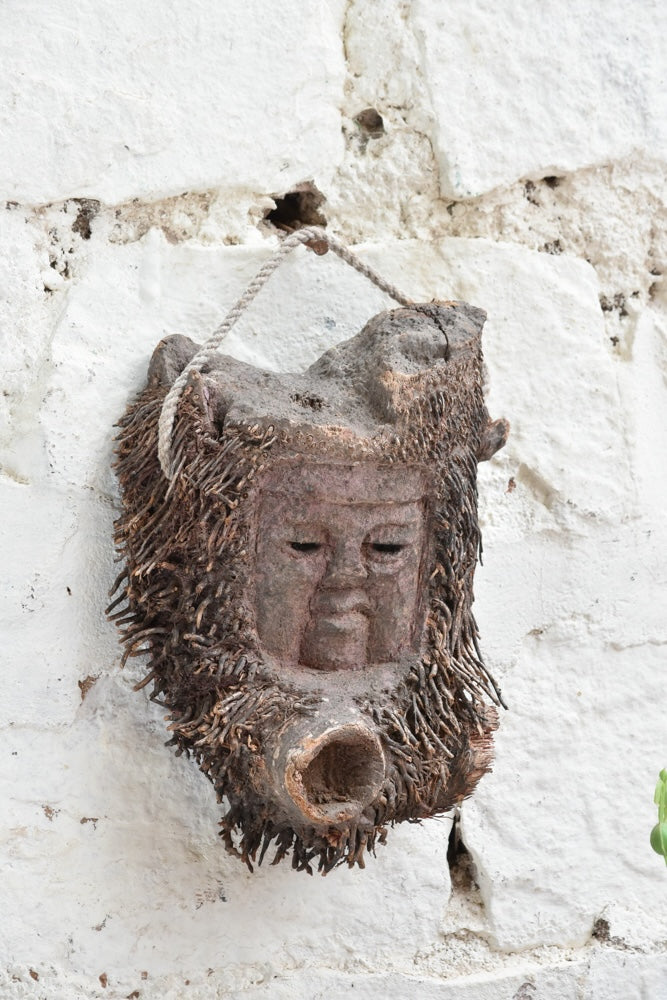 Angled view of Ekaurr Elder Spirit wall mask showing deep-carved facial features and antique patina finish