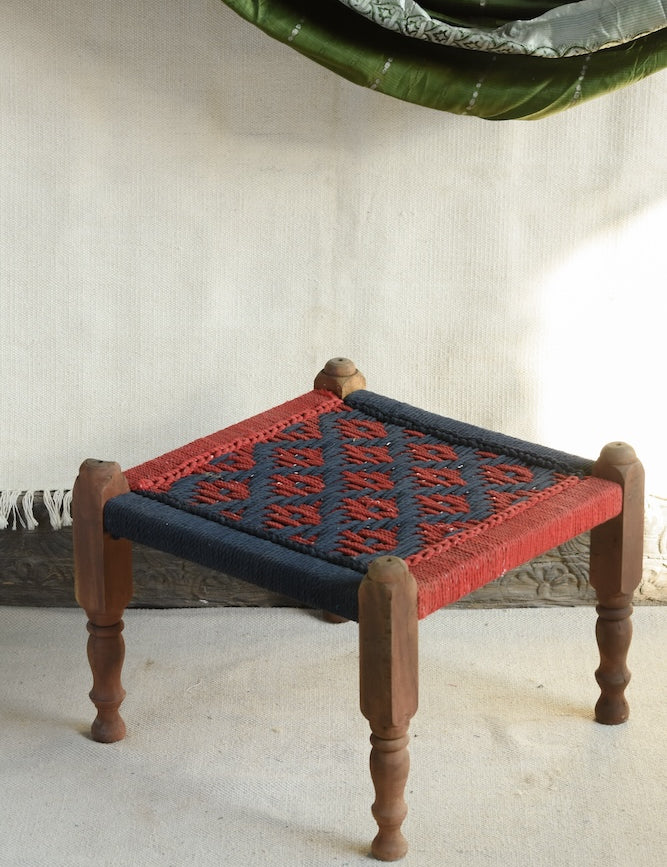 Handcrafted charpai-inspired wooden stool with handwoven cotton seat, featuring traditional Indian weaving and vibrant patterns by Ekaurr