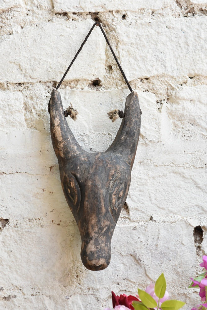 Close-up of Ekaurr Horned Sentinel wall mask showing hand-carved horn detailing and textured surface with aged finish