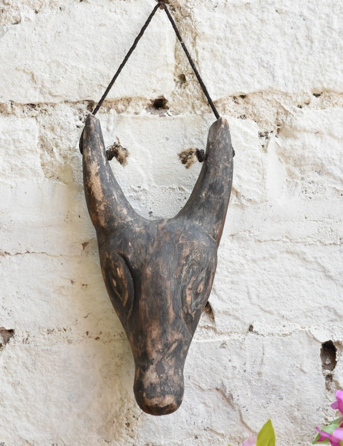 Close-up of Ekaurr Horned Sentinel wall mask showing hand-carved horn detailing and textured surface with aged finish