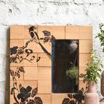 Ekaurr Morning Perch Mirror hand-painted bird on a blooming branch across individually grained reclaimed wood tiles framing a clear mirror panel at 30x30 inches, artisan one-of-a-kind wall mirror for living rooms and entryways