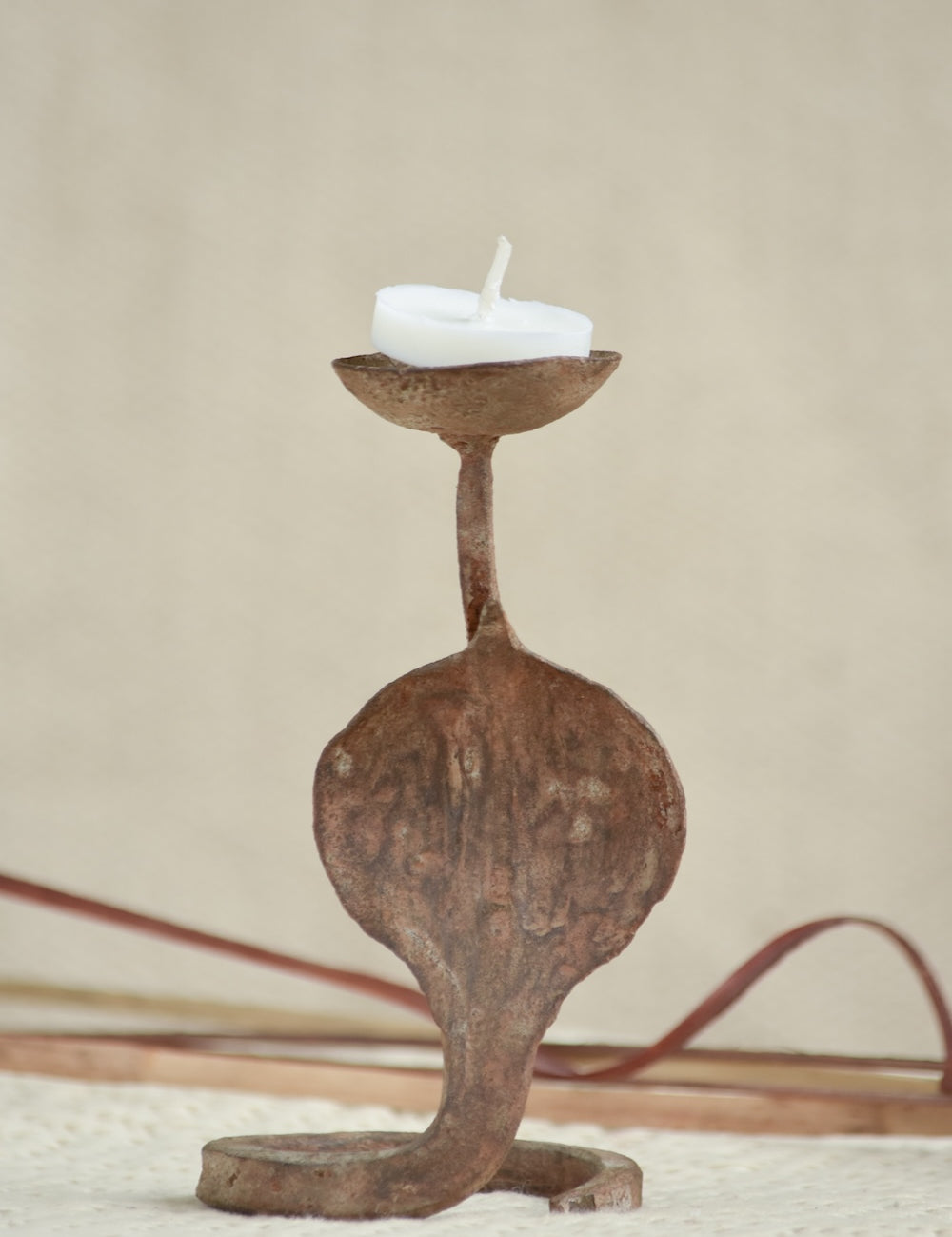 Ekaurr Rustic Snake Iron Candles styled with lit candles showing the snake form silhouette in warm candlelight against a home setting