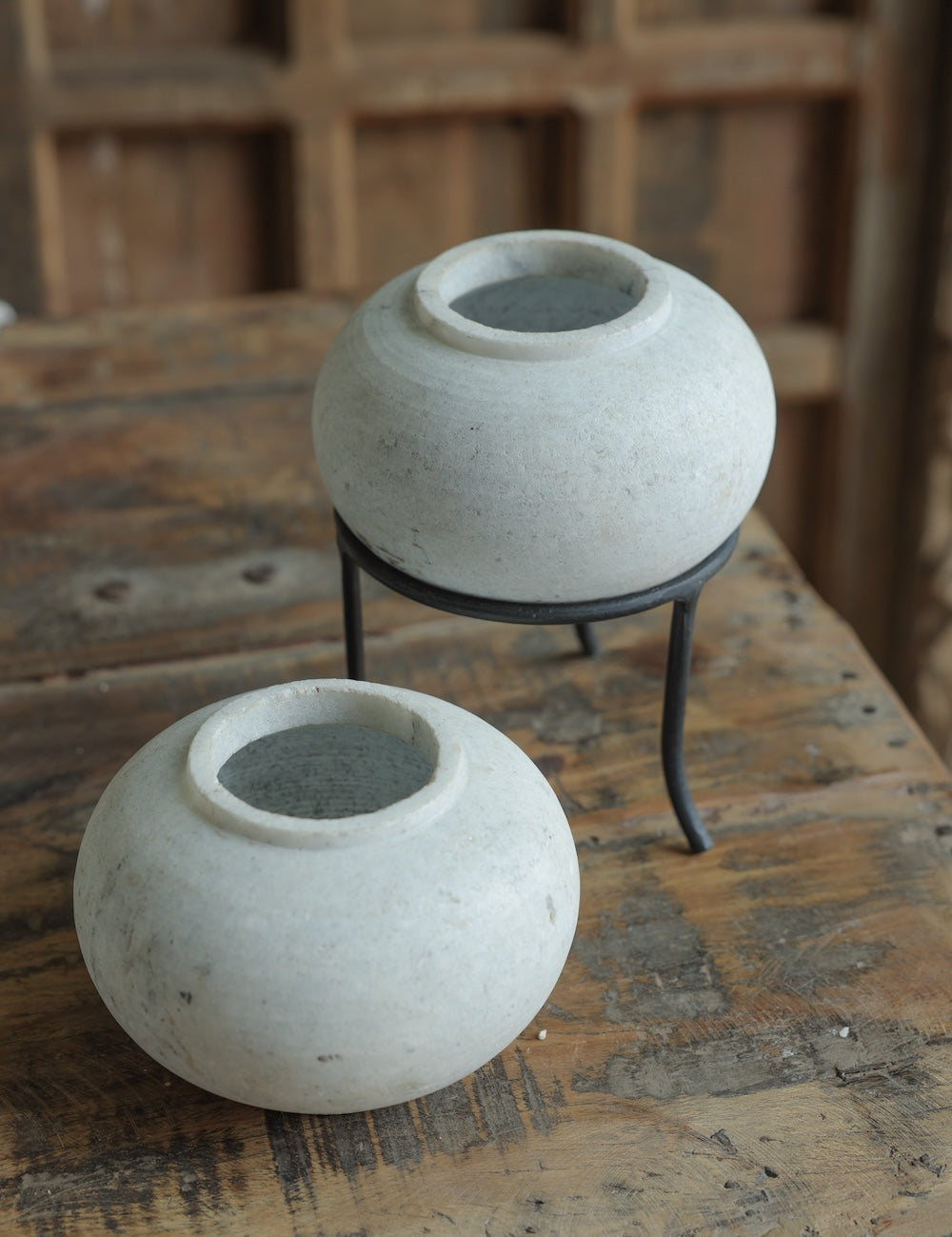 Ekaurr Set of 2 Round Marble Pots with subtle grey veins, hand-carved into round form, one elevated on a black iron stand, elegant stone planters or decorative bowls