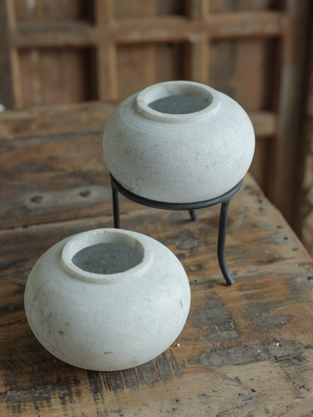 Ekaurr Set of 2 Round Marble Pots with subtle grey veins, hand-carved into round form, one elevated on a black iron stand, elegant stone planters or decorative bowls