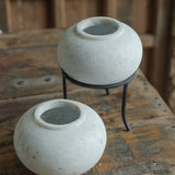 Ekaurr Set of 2 Round Marble Pots with subtle grey veins, hand-carved into round form, one elevated on a black iron stand, elegant stone planters or decorative bowls
