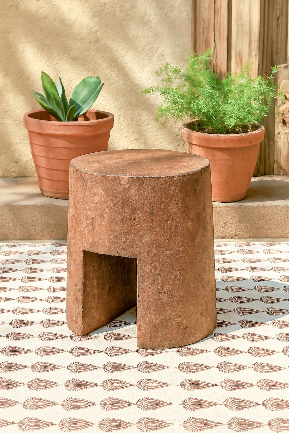 Ekaurr Solid Wood Chiseled Stool hand-carved from reclaimed wood with bold monolithic form, round top and arched base for rustic or contemporary interiors