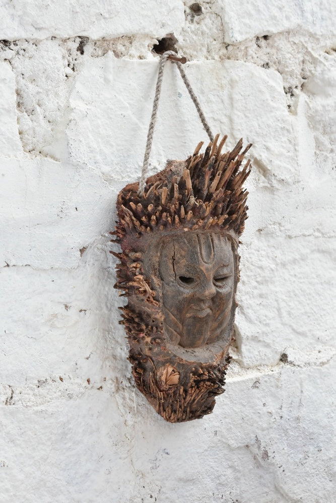 Ekaurr The Flame Keeper Mask shown at angle revealing carved bark-textured surface and raw natural wood tones, ancient elemental guardian wall décor piece