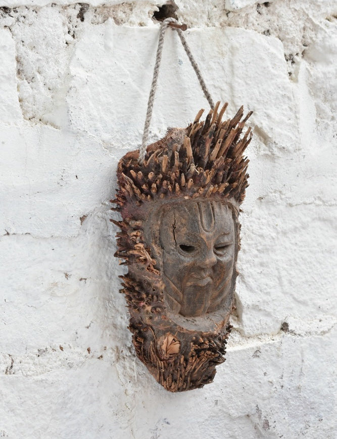 Ekaurr The Flame Keeper Mask shown at angle revealing carved bark-textured surface and raw natural wood tones, ancient elemental guardian wall décor piece